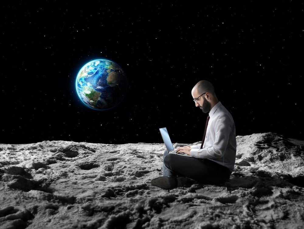 Earth viewed from the moon with a man working on a laptop in space.
