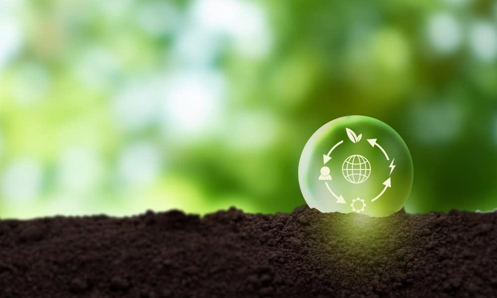 Sustainable development concept with eco-friendly globe and recycling symbols on soil.